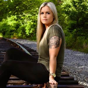 Blonde girl with green shirt sitting on train tracks