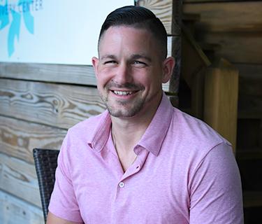 Headshot of man in pink shirt